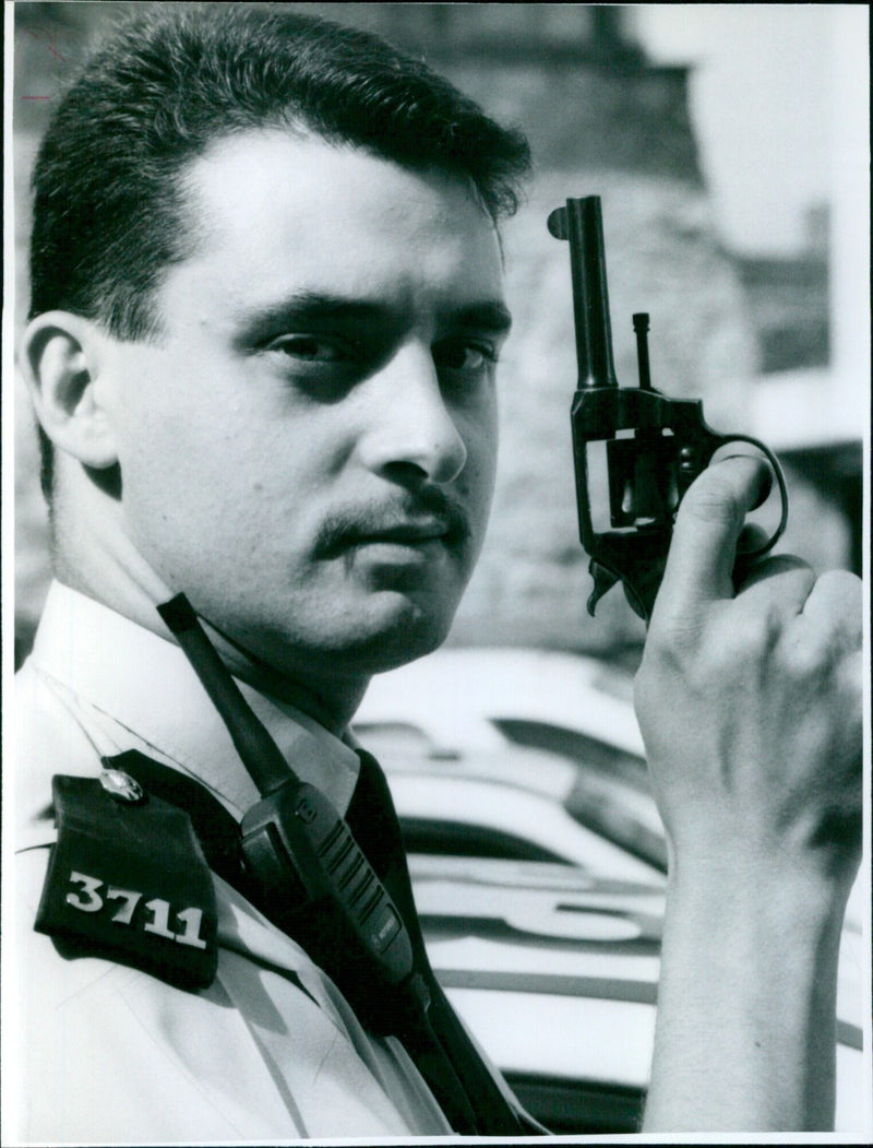 PC Giovanni Aufiero of Abingdon Police Station holds a 1930s .32 Colt pistol believed to have been brought to Britain from America during WWII. - Vintage Photograph