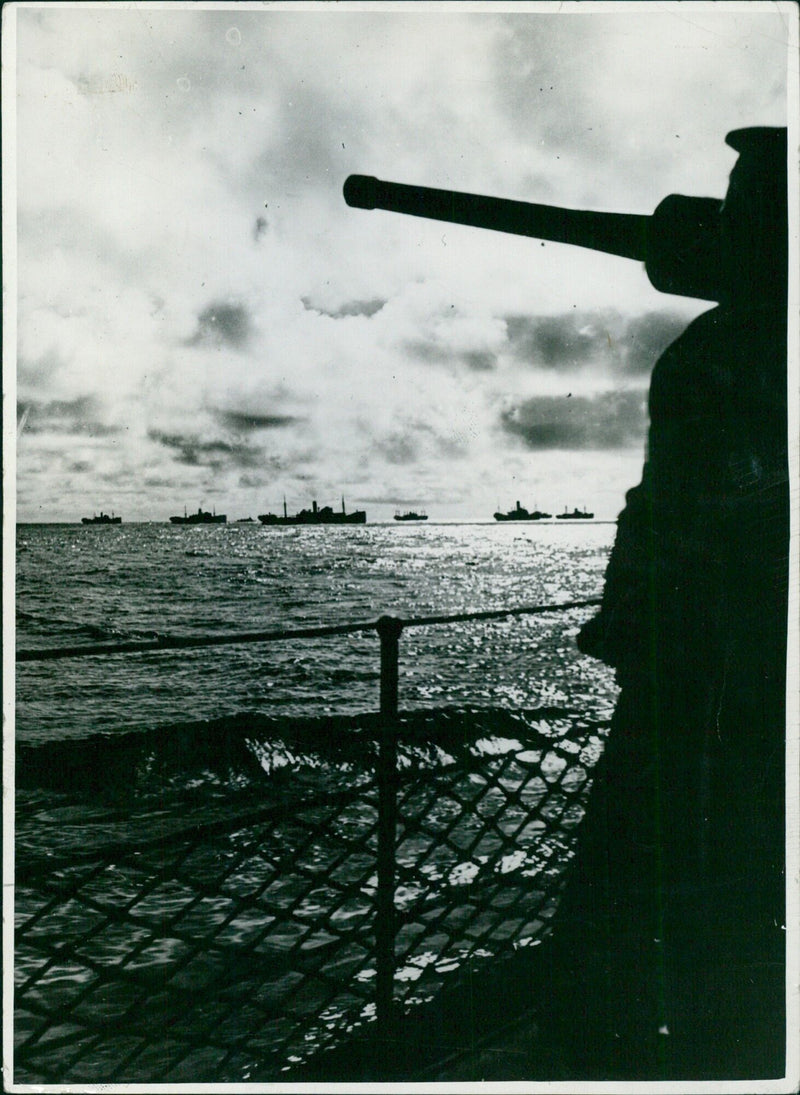 A convoy of British and French warships escort an Allied convoy in the setting dusk, providing protection against enemy forces during WWII. - Vintage Photograph