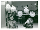 Stephen Farrell, aged eleven, and Timothy Eiston, aged eight, look at the papier mache heads on display at Luton's Children's Library, showing how to put rubbish to good use. - Vintage Photograph