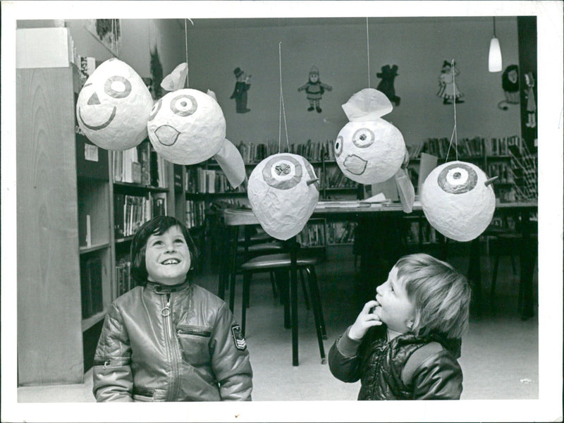 Stephen Farrell, aged eleven, and Timothy Eiston, aged eight, look at the papier mache heads on display at Luton's Children's Library, showing how to put rubbish to good use. - Vintage Photograph