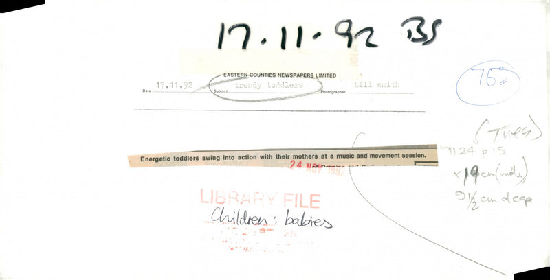 Energetic toddlers swing into action with their mothers at a music and movement session. - Vintage Photograph