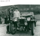 Young enthusials look over one of the veteran cars. - Vintage Photograph