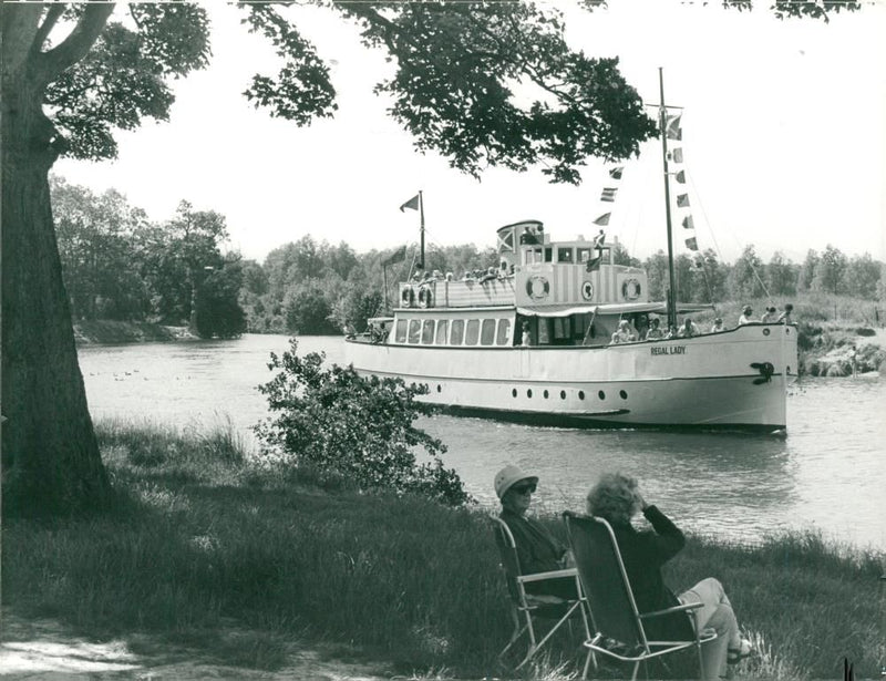 Relaxing in the shade of an oak tree as the pleasure boat Regal Lady glides past. - Vintage Photograph