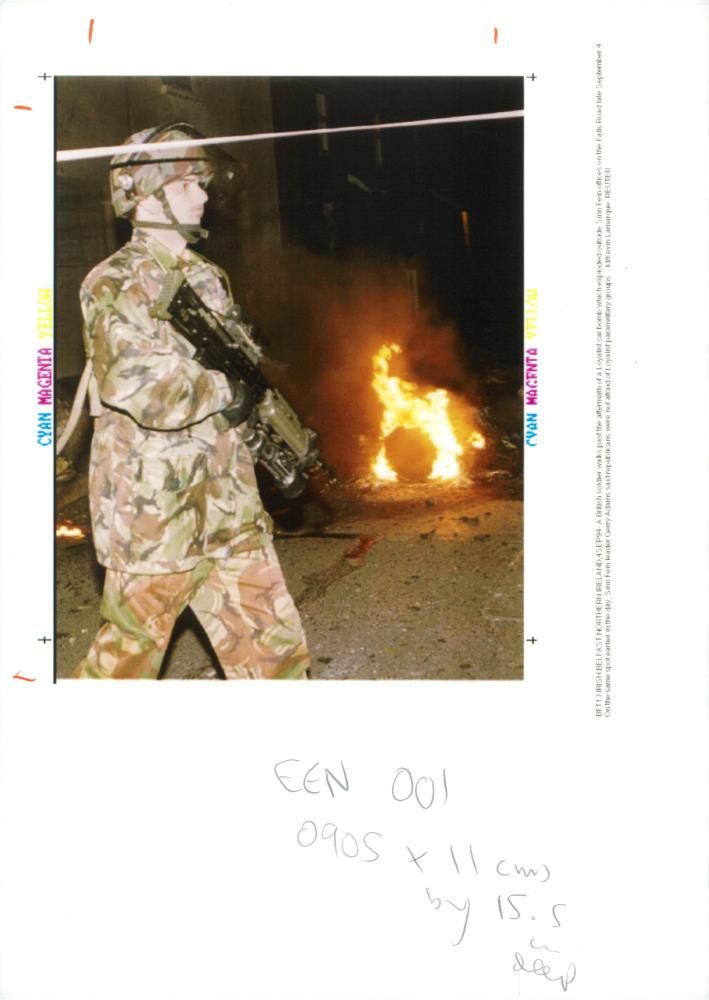 A British soldier walks past the aftermath - Vintage Photograph