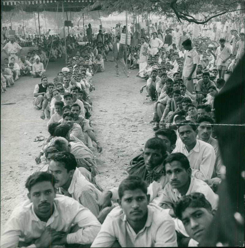 INDIANS SQAUTTING ON THEIR HAUNCHES IN LINES OUTSIDE A RECRUITING OFFICE. - Vintage Photograph