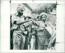 AN INDIAN SOLDIER CLAMPING A CHAIN ON THE ARM OF A PRISONER. - Vintage Photograph
