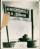 A heavy British tank passes behind the sign. - Vintage Photograph