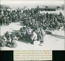 Squatting on boxes on the libyan sands are large groups. - Vintage Photograph