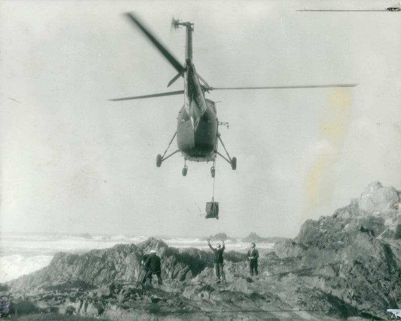 A helicopter delivering essential supplies Les Hanois lighthouse. - Vintage Photograph