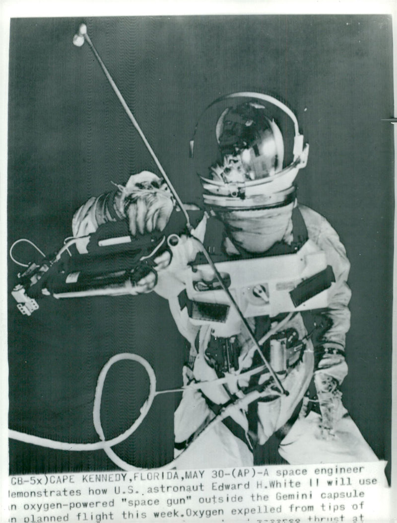 A space engineer demonstrates how astronaut Edward H. White II will use an "aerospace gun" with oxygen - Vintage Photograph