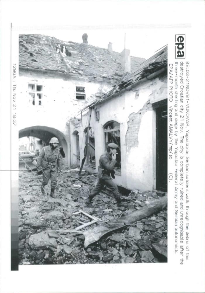 Serbian soldiers walk through the debris. - Vintage Photograph