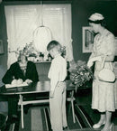 King Gustaf Adolf writes his name in the Larsson family book, in their cabin in Ãngby. Queen Elizabeth and 10-year-old Hans Larsson. - Vintage Photograph