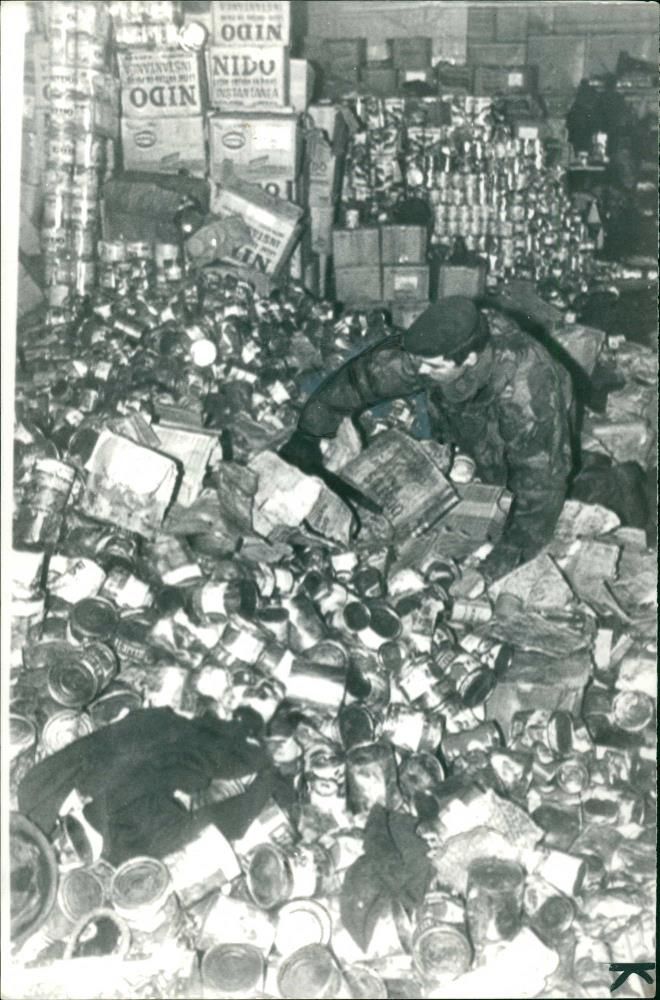 A paratrooper checking a mountain of Argentine tinnned food - Vintage Photograph