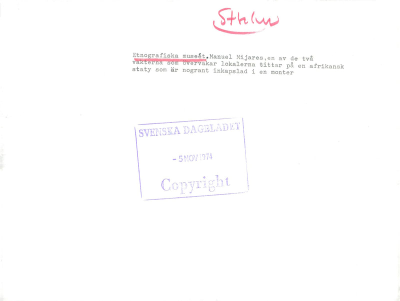 The Ethnographic Museum Guard Manuel Mijares looks at an African statue that is carefully enclosed in a booth - Vintage Photograph