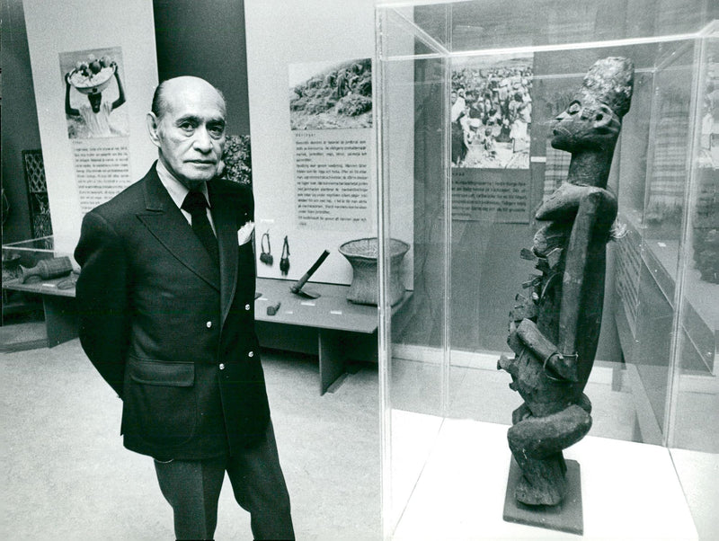 The Ethnographic Museum Guard Manuel Mijares looks at an African statue that is carefully enclosed in a booth - Vintage Photograph