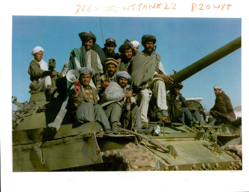 Taliban religious fighters ride on a captured tank. - Vintage Photograph