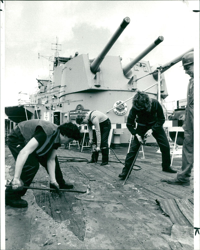 Shipwright apprentices renewing planking on the quarterdeck of the HMS Belfast in London, 18.04.1986. - Vintage Photograph