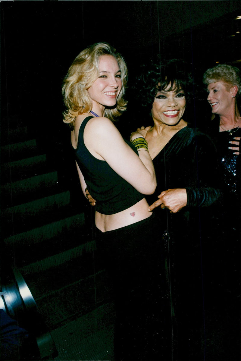 Eartha Kitt points to a tattoo of a heart on her adopted daughter Kate Shapiro at the premiere of "The Wizard of Oz" on Broadway - Vintage Photograph