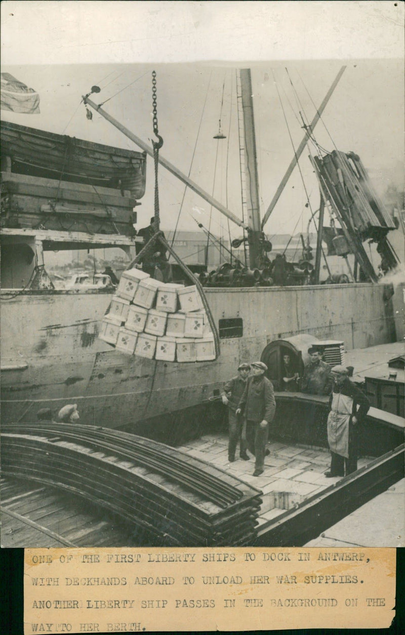 One ofg the first liberty ships to dock in antwef with deckhands. - Vintage Photograph