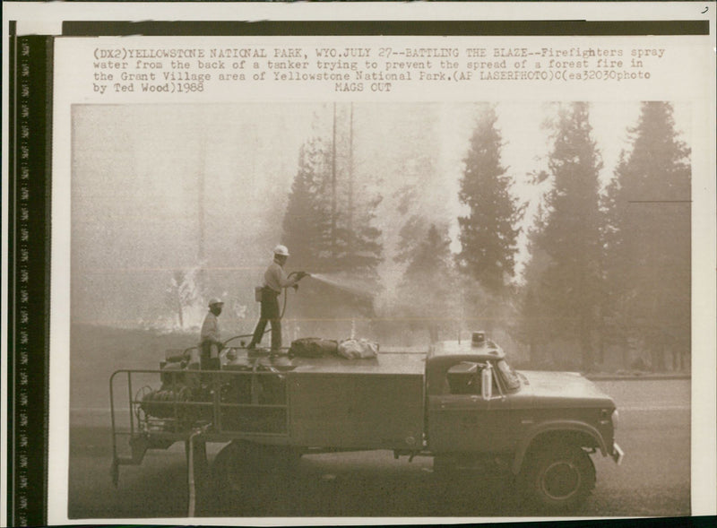 fire fighters spray water from the back of a tanker. - Vintage Photograph