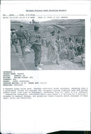 Rwanda war:a rwandan woman walks past rwandan patriotic front soldier. - Vintage Photograph