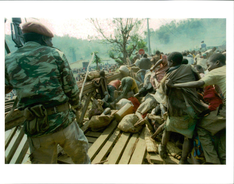 A Zairan soldier attempts to push back a crowd of panic-stricken Rwandan refugee. - Vintage Photograph