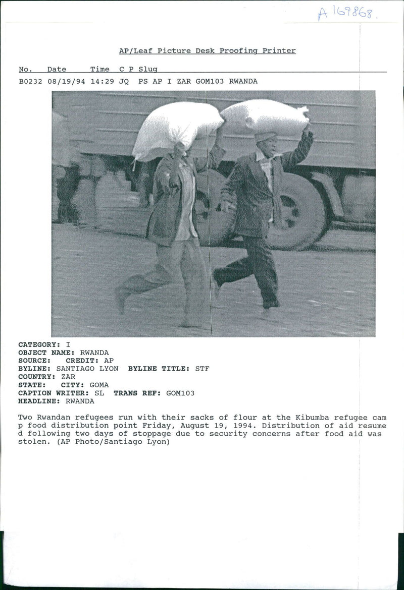 Rwanda war:two rwandan refugees run their two sacks of a flour kimbumba. - Vintage Photograph