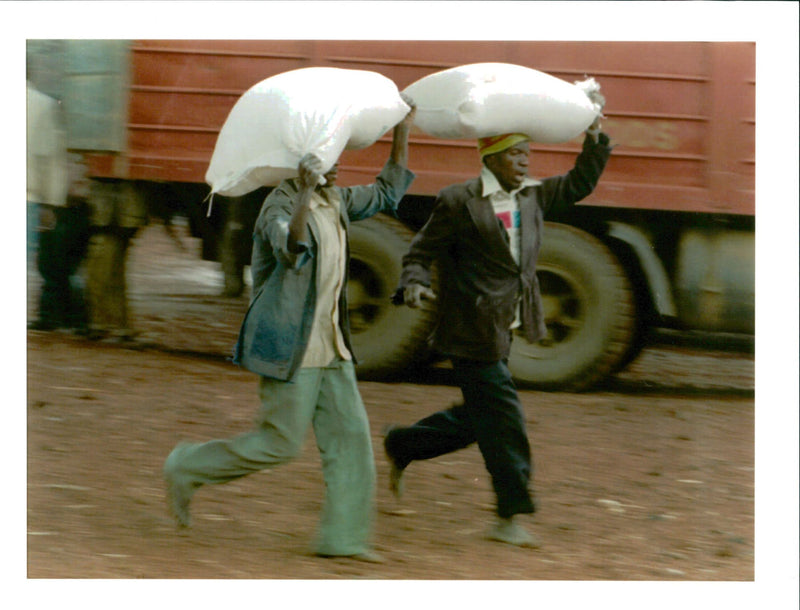 Rwanda war:two rwandan refugees run their two sacks of a flour kimbumba. - Vintage Photograph