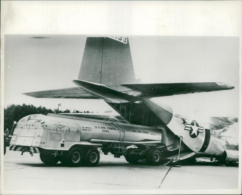 Oil tanker drives into the belly of a Lockheed C-130 Hercules cargo plane, 1955. - Vintage Photograph