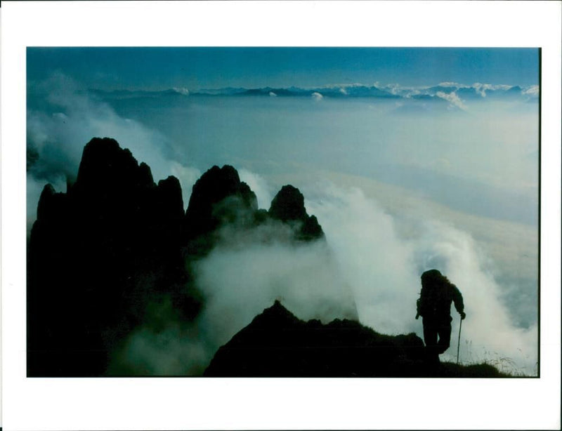 A mountain climber is silhouetted against the clouds. - Vintage Photograph