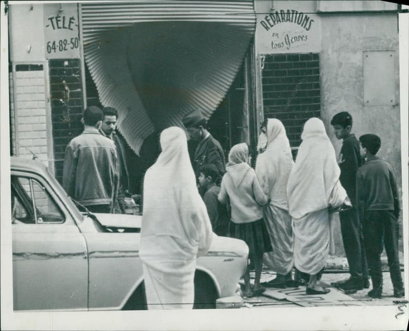 Algeria Riots:veiled moslem women and children looking at one of the damage shops. - Vintage Photograph