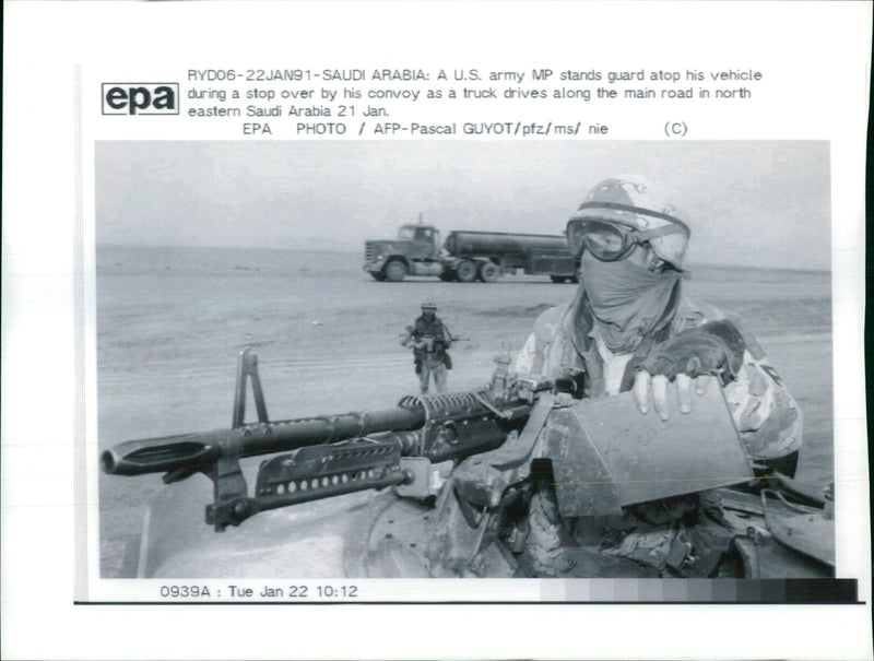 A U.S army MP stands guard atop his vehicle during a stop over. - Vintage Photograph