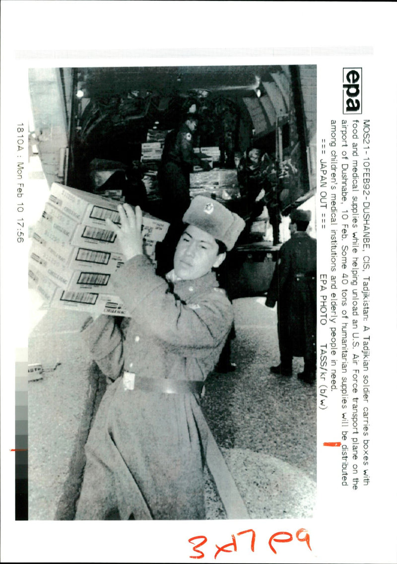A Soldier in Tajikistan unloads supplies from an American plane. - Vintage Photograph
