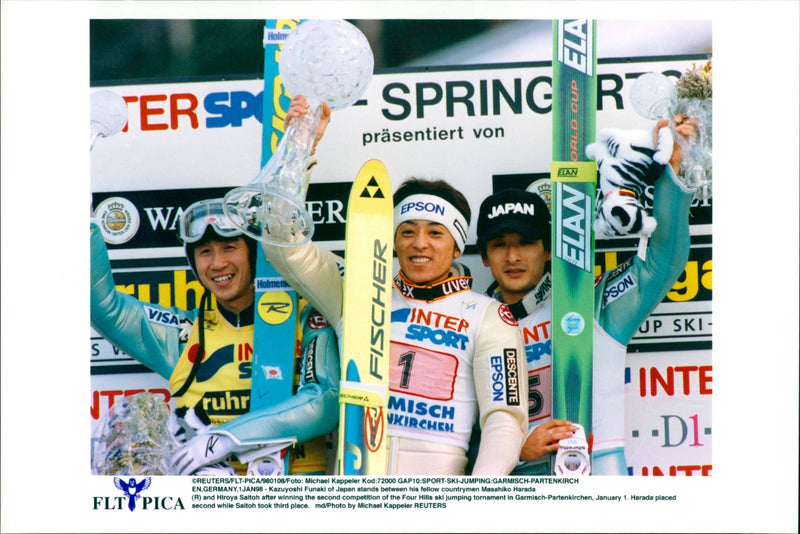 Kazuyoshi Funaki of Japan stands between his fellow countrymen Masahiko Harada (R) and Hiroya Saitoh after winning the second competition of the Four Hills ski jumping tournament. - Vintage Photograph