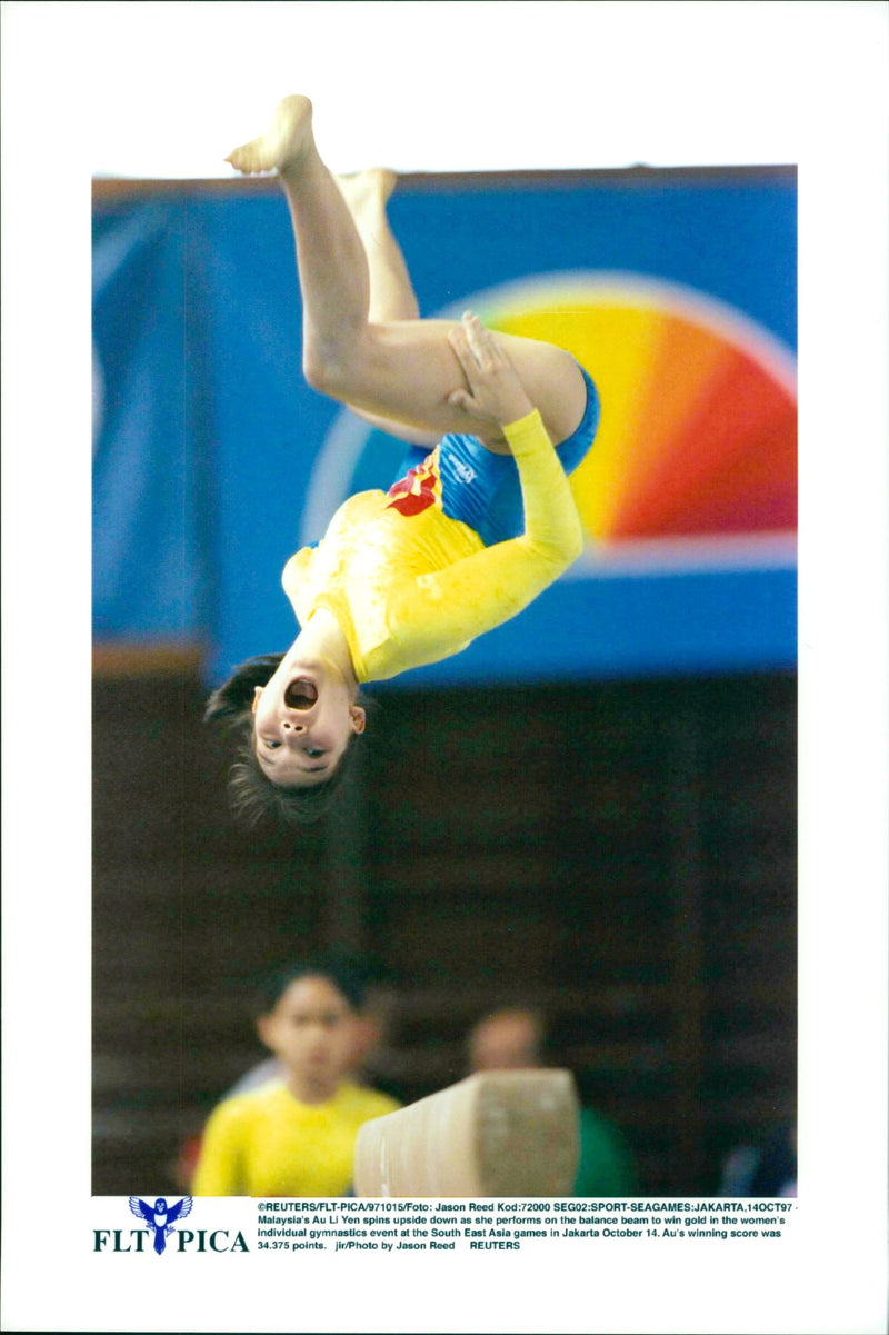 Malaysia's Au Li Yen, spins upside down as she performs on the balance beam to win gold in the women's individual gymnastics event at the South East Asia games in Jakarta. - Vintage Photograph