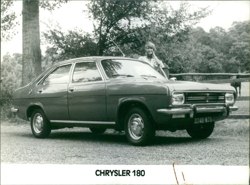 A view of Chrysler 180 parked next to a farm. - Vintage Photograph