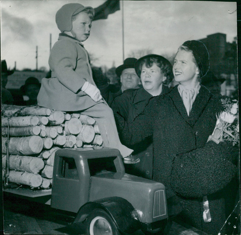 Princess Sibylla holds Prince Carl Gustaf who sits on the model car's lumber yard - Vintage Photograph