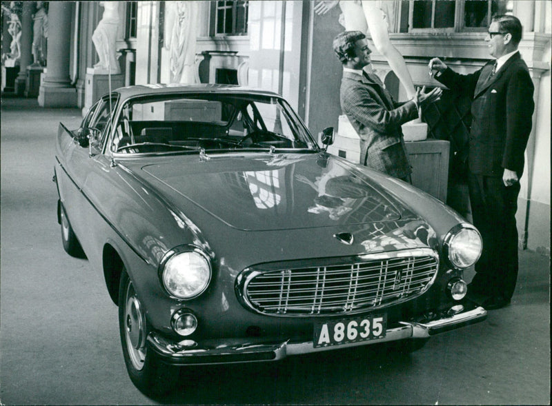 Crown Prince Carl Gustaf becomes the owner of a sky blue Volvo P1800. Volvo's PR manager Hans Blenner hands over the car - Vintage Photograph