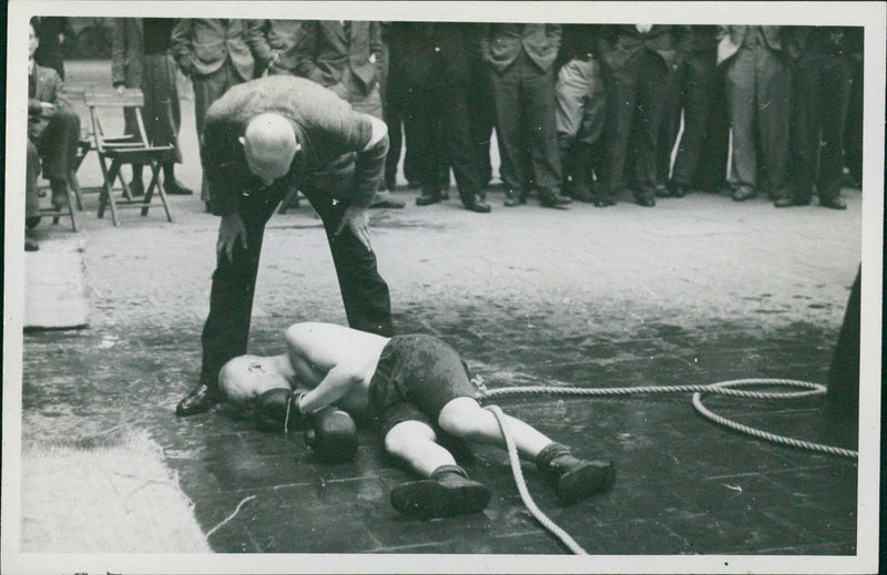 A referee checking on a boxer who has been knocked out. - Vintage Photograph