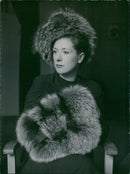 A woman wearing an animal fur hat and holding animal skin shag rug - Vintage Photograph