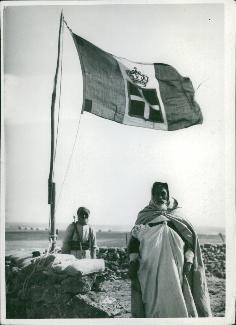 Locals in Africa standing under the flag of the Kingdom of Italy - Vintage Photograph