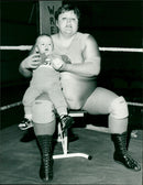 Klondyke Kate, a female wrestler, is pictured with her baby Adam and the baby's father, Ian Dean. She continued to compete while 8 months pregnant and was unaware of her pregnancy. - Vintage Photograph