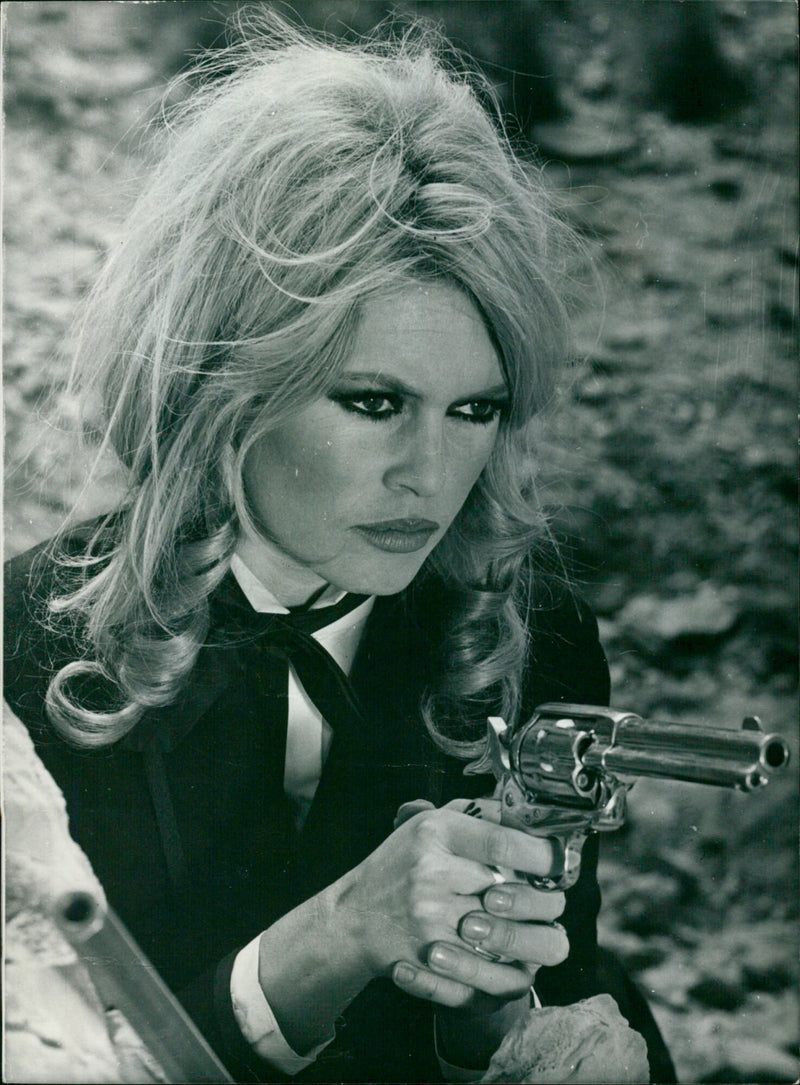 French film star Brigitte Bardot holds a six shooter gun ready to kill her first Apache. - Vintage Photograph