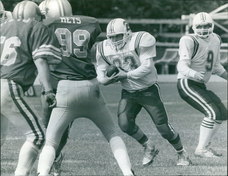 American football player Stan Walters runs with the ball during a London Mets game. - Vintage Photograph