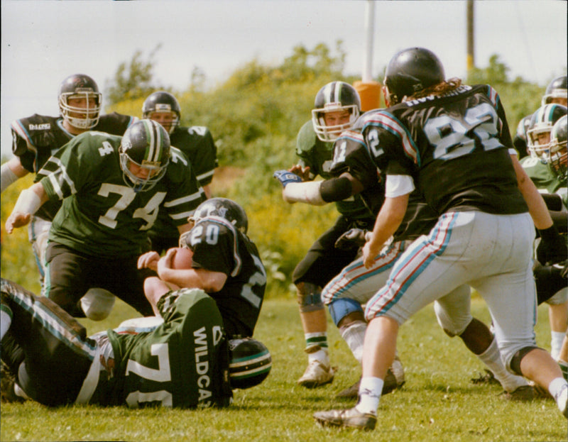 American Football players from the Carterton Wildcats and Gwent Mustangs compete in a match. - Vintage Photograph