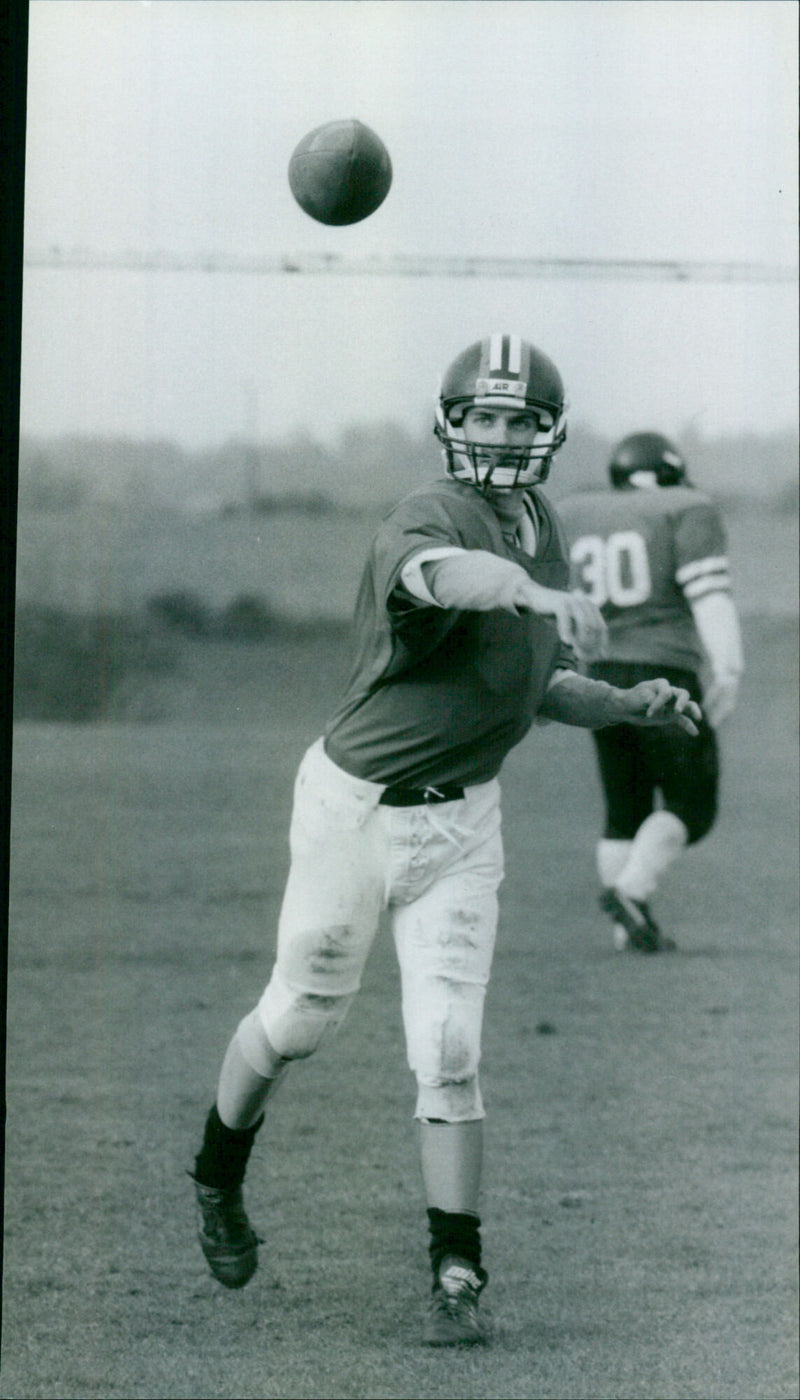 Quarterback Mark Blake of the Carterton Wildcats American Football team throws a pass during a game. - Vintage Photograph