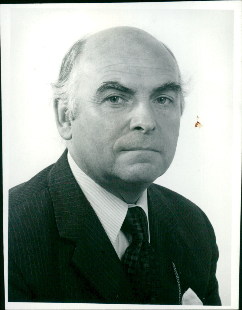 A man stands in a field of wildflowers, smiling and holding a bouquet of blooms. - Vintage Photograph