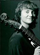 Musician Sarah Cunningham plays the viola da gamba outside of Buckingham Palace Road in London. - Vintage Photograph