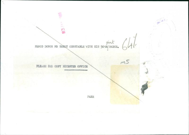 Mr Harry Constable proudly holds up his 50th pint badge at a blood donation center. - Vintage Photograph