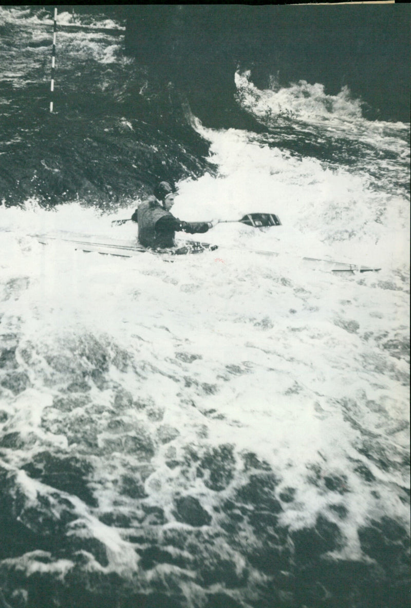 Julian Howells and Robert Doman, international slalom canoeists, practice white water canoeing in the rain. - Vintage Photograph
